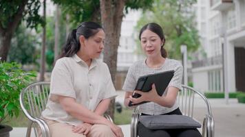 Collaboration under the sun. Two people engage in creative conversation in a quiet outdoor setting, fostering connection and communication while sharing insights via a digital tablet. video