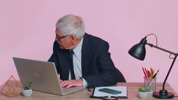 Worried senior businessman sits at workplace avoid working and playing racing or shooter games video