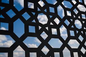 Fluffy white clouds in a blue sky. View through the window grate photo