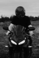 A motorcycle driver wearing a helmet is sitting on a sports motorcycle. The glitch effect photo