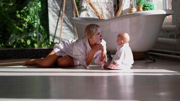 A woman in a bath robe and a baby on the floor video