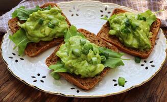 Sandwich with spinach, avocado, green peas and egg on wood background photo