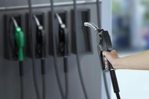 Man is Holding a fuel nozzle against with in a service station blurred background photo