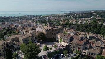 Aerial view of a coastal town with a historic building in the center. The scene includes green trees, rooftops, and the sea in the background. Historic architecture, social media posts about France video