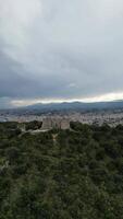 Aerial view of an ancient fortress surrounded by lush greenery and mountains. The sky is overcast, creating a dramatic atmosphere. video