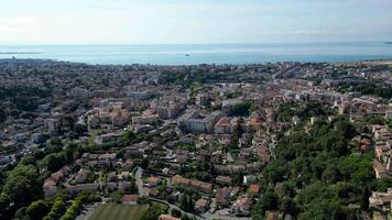 Aerial view, coastal town with a mix of residential buildings, greenery, and the ocean in the background. Clear skies and a serene atmosphere. Cultural documentaries, historic architecture video