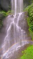 lento movimento fpv zangão tiro subindo acima a espirrando sekumpul cascata dentro Bali, Indonésia, Aumentar a partir de a água superfície com cinematográfico movimento e tropical cenário. video