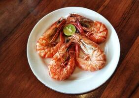 A plate of shrimp with a lime wedge on top photo