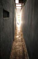 A narrow alleyway with a blue wall and a car parked in the distance photo