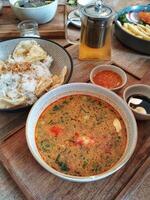 A bowl of soup and a plate of rice on a wooden table photo