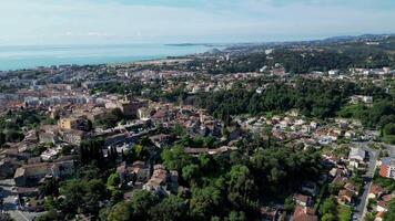 Aerial view of a coastal town with a mix of residential buildings, greenery, and the ocean in the background. Clear skies and a serene atmosphere. Cultural documentaries, historic architecture video