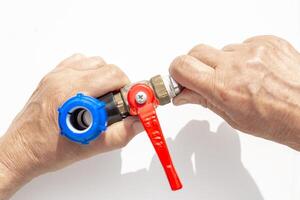 Closeup of hands assembling metal threaded faucet part with blue plastic fittings and red valve photo