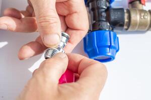 close-up of hands assembling metal threaded part with plastic fittings, winding fumka, sealing tape photo
