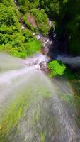 fpv zangão tiro subindo acima a espirrando sekumpul cascata dentro Bali, Indonésia, Aumentar a partir de a água superfície com cinematográfico movimento e tropical cenário. video