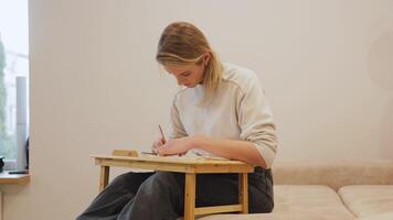 young woman enjoys drawing, cleaning a flowerpot, working with a laptop, and reading a book while relaxing on a sofa video