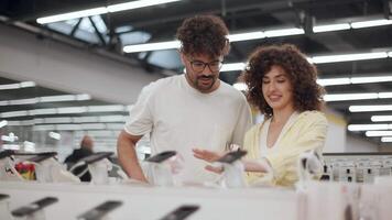 Customers browsing electronic store displays, carefully selecting smartphone accessories, comparing chargers and cables while making purchasing decisions together video