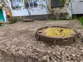 A rusty metal pipe is sitting on the ground in front of a house. The pipe is yellow and has a hole in it. The scene is somewhat eerie and gives off a feeling of decay and neglect photo