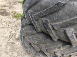 The tire is old and worn, with a lot of dirt and grime on it. It's a tire on a tractor, and it's not in good condition photo