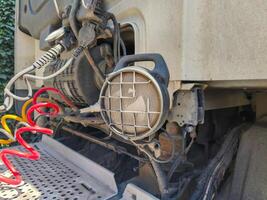 A dirty truck with a red and yellow tire on the back. The tire is in the process of being removed photo