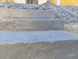 A gray staircase with a white railing. The steps are painted gray and the railing is silver. The stairs are made of concrete and the railing is made of metal photo