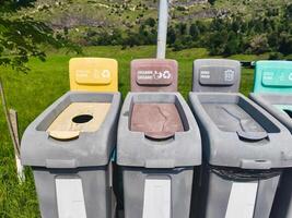 A row of trash cans with different colored lids and signs on them. The trash cans are labeled for different types of waste, such as plastic, paper, and organic materials photo