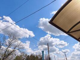 A blue sky with clouds and a white umbrella. The umbrella is open and is providing shade. The sky is clear and bright, and the clouds are scattered throughout the sky. The scene is peaceful photo