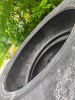 A tire with a hole in it is shown in a forest. The tire is black and has a hole in the middle. The tire is surrounded by trees and bushes, giving the image a natural and peaceful feel photo