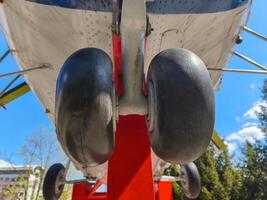 The wheels of an airplane, with the wheels being black and red. The wheels are positioned on a red post, and the image has a bright and sunny atmosphere photo