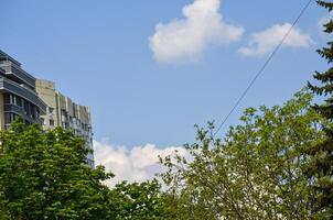 A clear blue sky with a few clouds and a tall building in the background. The sky is a beautiful backdrop for the cityscape photo