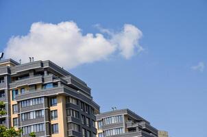 A tall building with a cloudy sky in the background. The sky is blue and the clouds are white photo