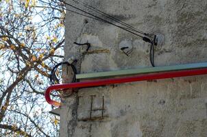 A red pipe is attached to a building. The pipe is located on the side of the building and is connected to a wire photo