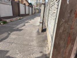 A street with a brick wall on the side. The wall is brown and has a few cracks photo