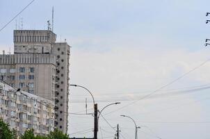 A tall building with a lot of windows and a cloudy sky in the background. The sky is overcast and the building is grey photo