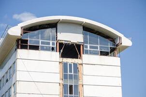 A building with a large window on the top floor. The window is broken and the building appears to be in disrepair photo