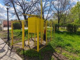 A yellow box with a red fire hydrant on top of it. The box is surrounded by a fence photo