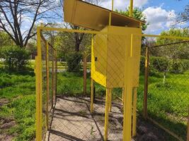 A yellow box with a fence around it. The box is empty and the fence is rusty. Scene is somewhat sad and lonely photo