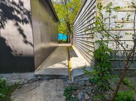 A concrete walkway with a yellow line on it. The walkway is next to a building with a black wall photo