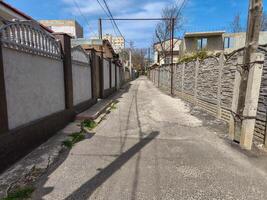 A street with a fence on both sides and a pole in the middle. The pole is holding a metal bar photo