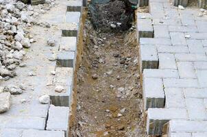A brick walkway with a hole in it. The hole is being dug out by a person photo