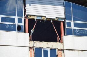 A building with a hole in the wall and a window with graffiti on it. The building appears to be in disrepair photo