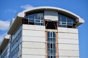 A building with a large window on the top floor. The window is open and the building appears to be in disrepair photo