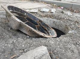 A broken pipe is in the ground with a hole in it. The hole is filled with water photo