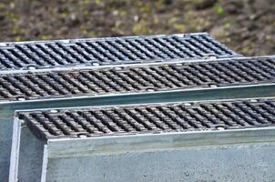 A row of metal grates are stacked on top of each other. The grates are black and silver, and they are arranged in a neat row. Concept of order and organization photo
