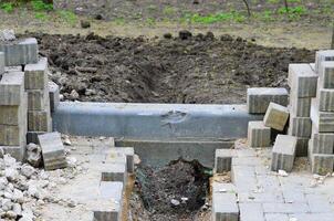 A pile of bricks is laying on the ground next to a trench. The bricks are in various sizes and are scattered around the area. The scene gives off a sense of construction or renovation work photo
