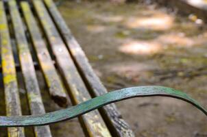 A bench with a green metal arm rests. The bench is old and has a yellow paint photo