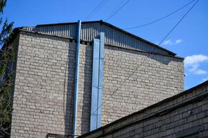 A building with a blue pipe on the side. The building is made of bricks. The sky is blue and clear photo