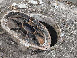 A rusty metal pipe is sitting in the ground with a hole in it. The hole is open and the pipe is missing photo