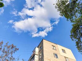 A building with a lot of windows and a cloudy sky in the background. The sky is blue and the clouds are white photo