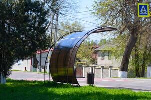A metal structure with a roof is sitting in a grassy area. The structure is a bus stop photo