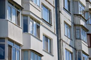 A tall building with many windows and a balcony. The windows are mostly clear, but some are dirty. The building appears to be old and run down photo